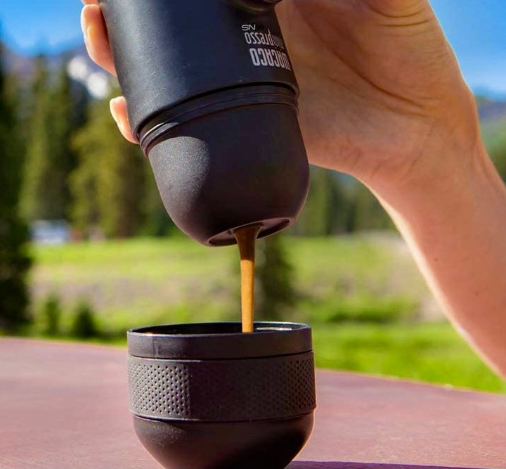 A person pouring an espresso from the Wacaco Minipresso.