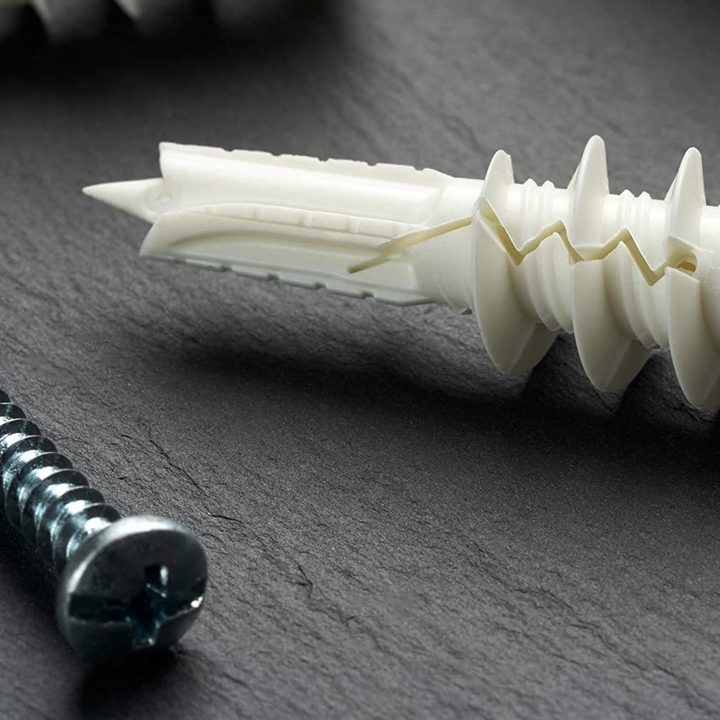 A number 8 sized screw next to its wall anchor for hanging a Nest Mini