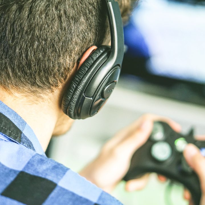 Gamer playing Xbox One with headset on.