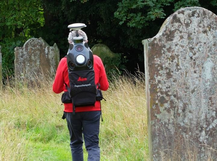 A person mapping a churchyard using a high-tech backpack.