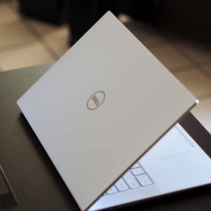 Dell XPS 15 OLED laptop sitting on a small table. View of the backside.