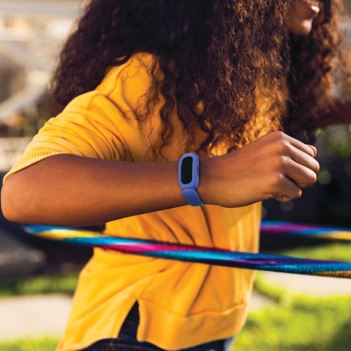 Fitbit Ace 3 worn around the wrist of a child using a hula hoop.