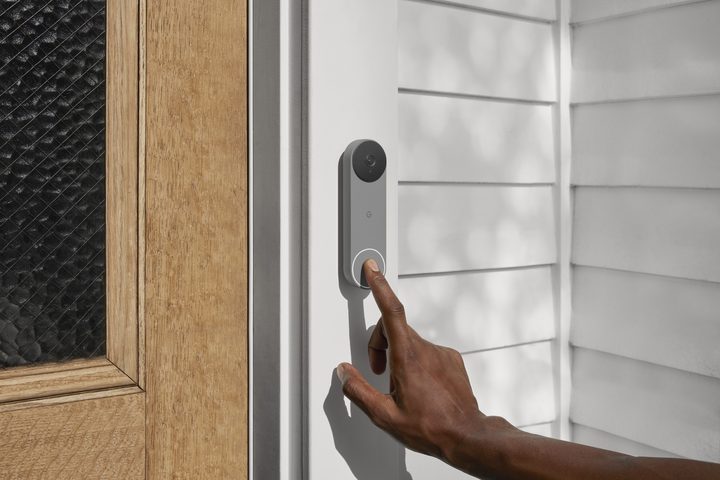A hand pressing the Nest Doorbell button.