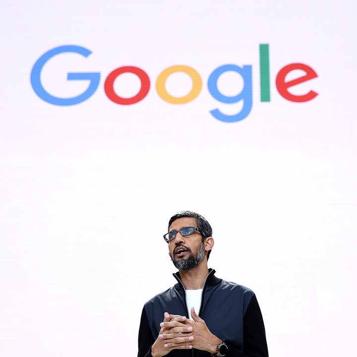 Google CEO Sundar Pichai stands in front of a screen showing the Google logo.
