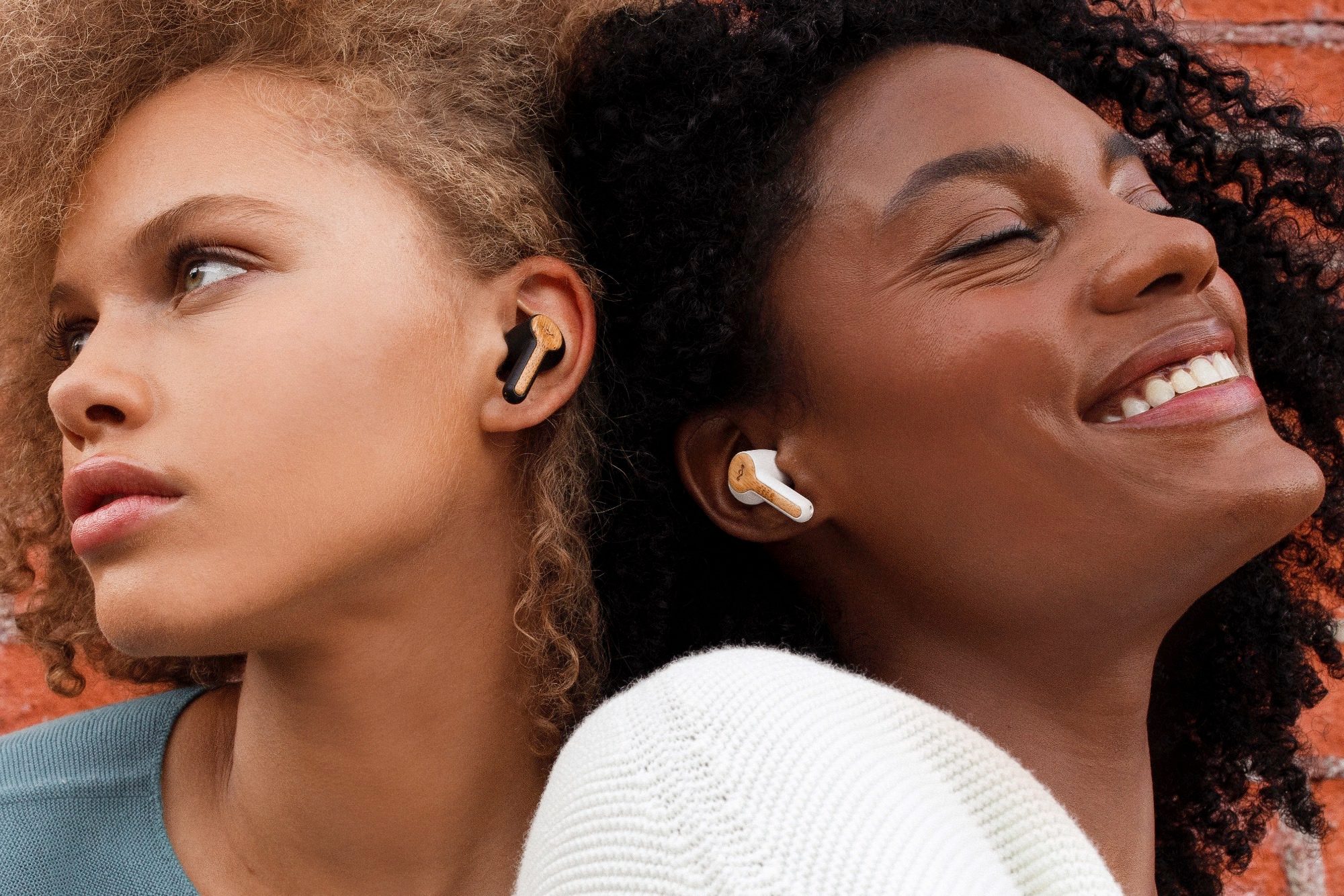 Two women wearing House of Marley Rebel True Wireless Earbuds.