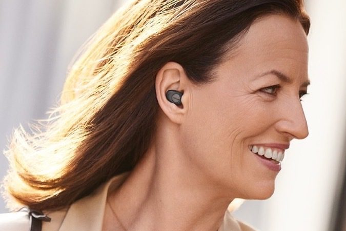 A woman wears Jabra Enhance Plus true wireless earbuds.