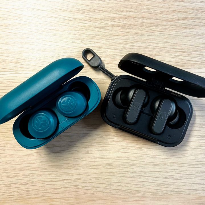 JLab Go Air Pop and Skullcandy Dime earbuds in charging cases with open lids.