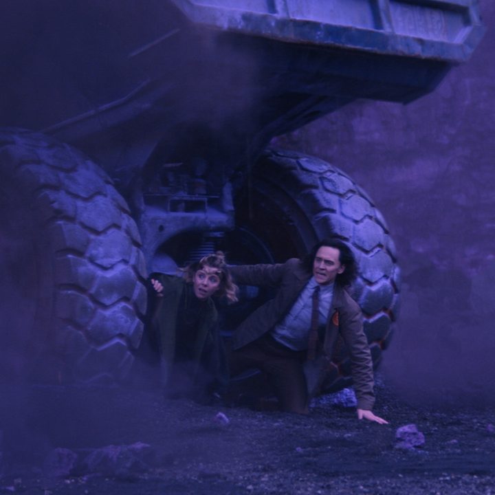Sophia Di Martino and Tom Hiddleston hide under a mining vehicle in Marvel's Loki series.