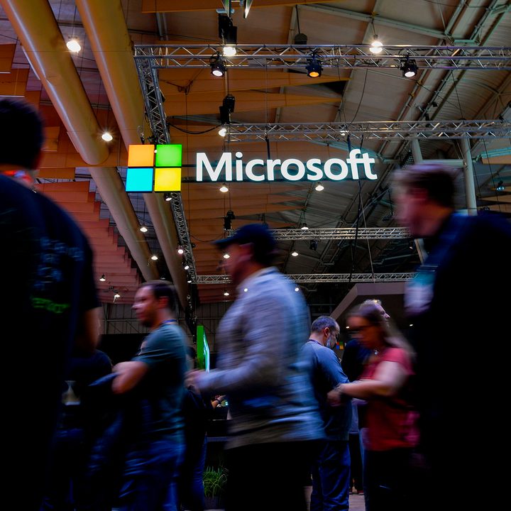 Attendees walk past the Microsoft logo during the Web Summit in Lisbon.