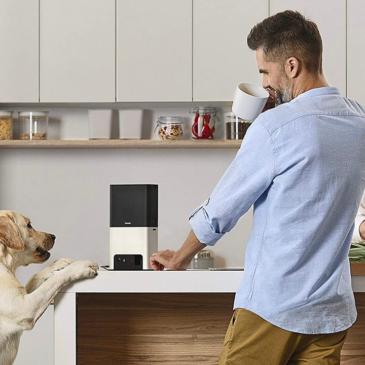 A dog and his human companions surrounding the Petcube Bites 2.