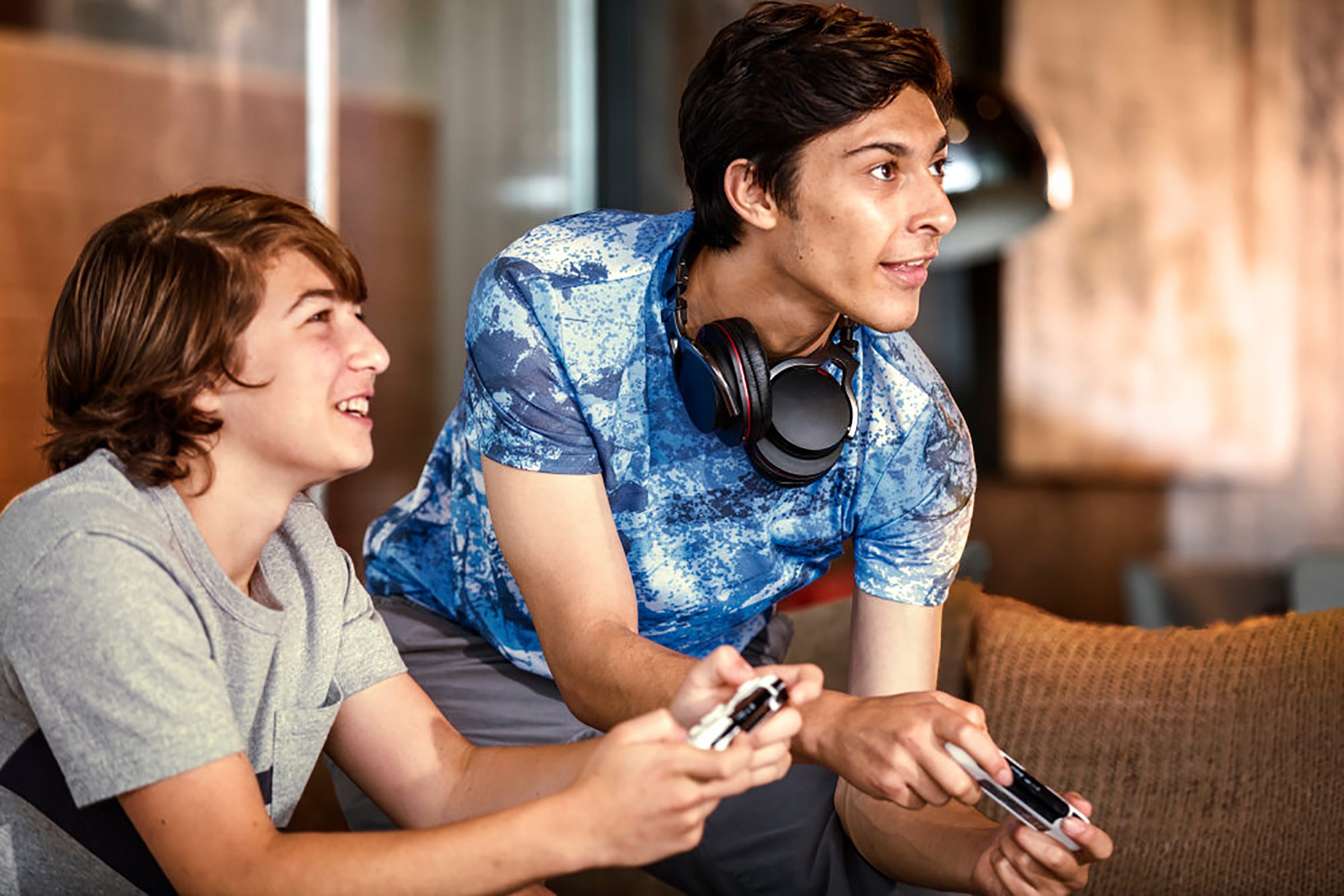 Teens with headphones playing video games.