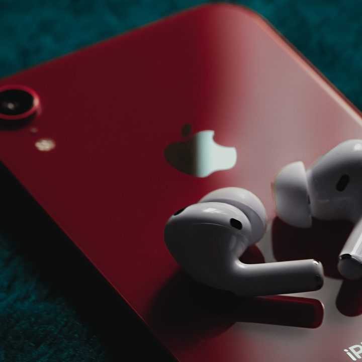 The AirPods Pro on top of a red iPhone.