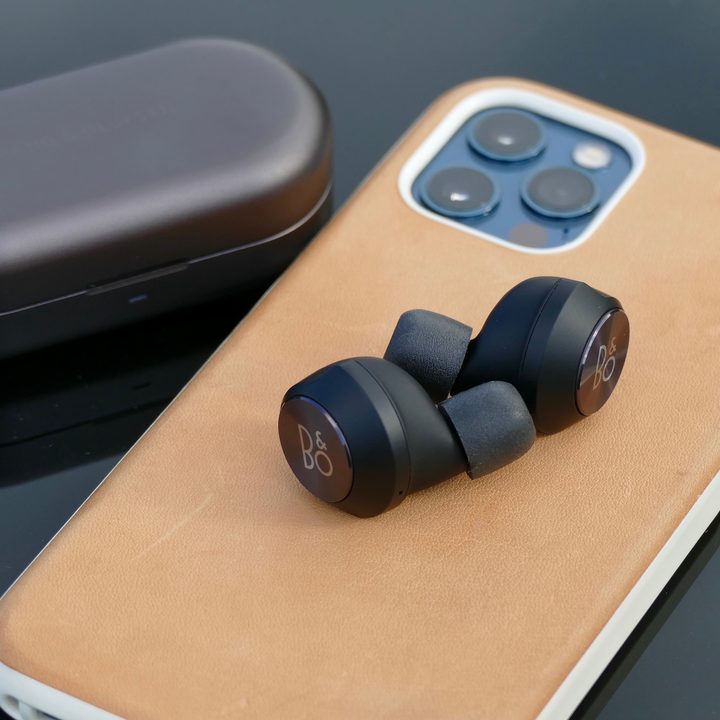 Beoplay EQ earbuds on top of an iPhone 12 Pro.