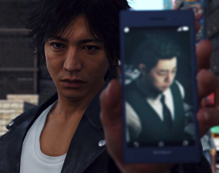 The main character of Judgment shows a picture on his phone to someone.