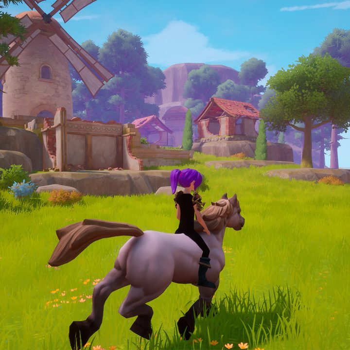 Riding a horse through the grass near a village.
