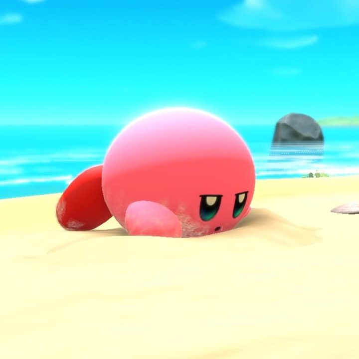 Kirby lays on the beach in Kirby and the Forgotten Lands.