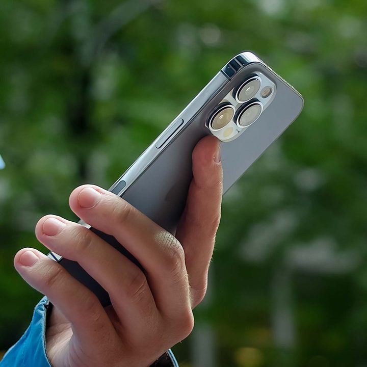 The iPhone 13 Pro from behind, being used in a single hand.