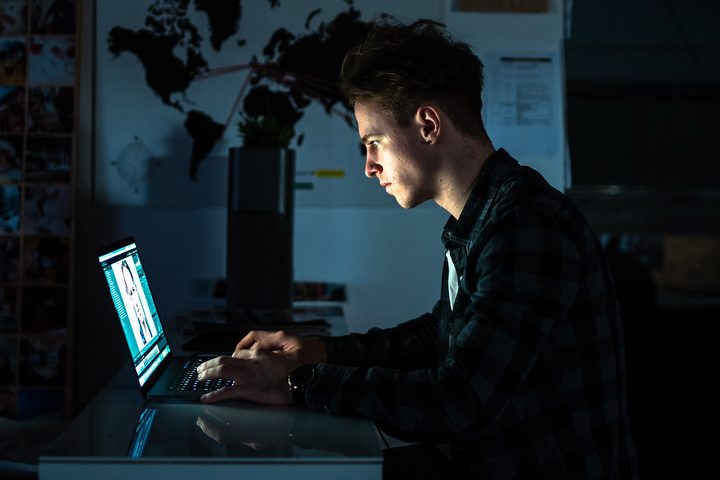 Man using a Macbook Pro at a desk.