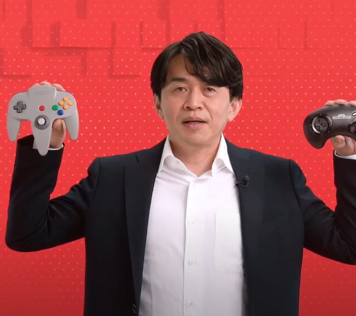 Yoshiaki Koizumi holding the N64 and Sega Genesis controllers for Nintendo Switch.