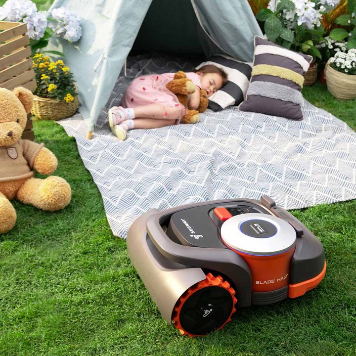 Navimow autonomous lawnmower riding by a sleeping child.
