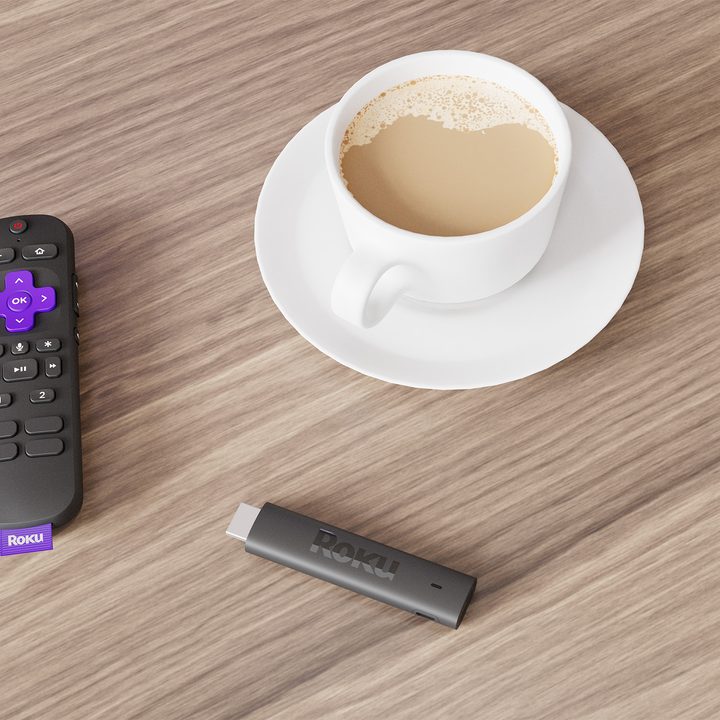 Roku Streaming Stick 4K and remote control on a table with coffee.