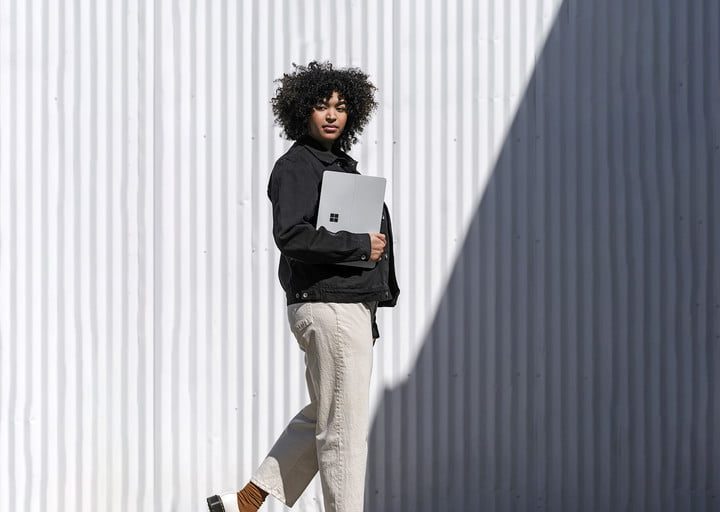 Woman walking with the Surface Laptop Studio in hand.