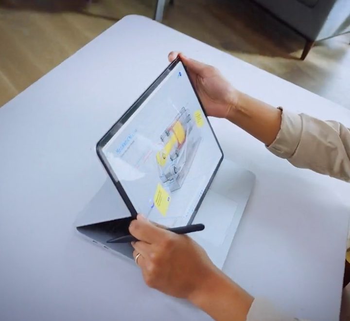 A hand manipulating the trackpad on a Microsoft Surface Laptop Studio.