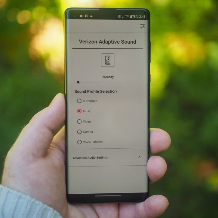 Hand holding an Android smartphone showing the Verizon Adaptive Sound menu.