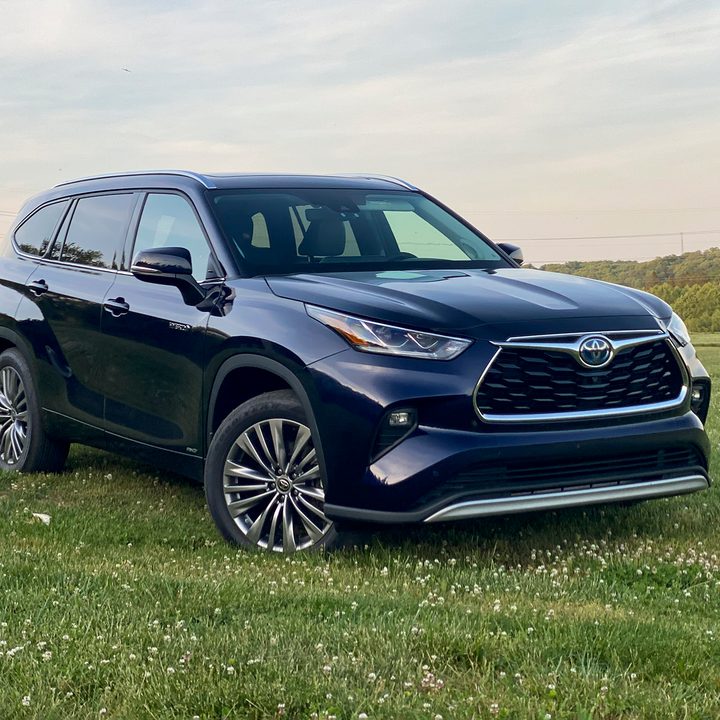 Angled front view of the 2021 Toyota Highlander Hybrid Platinum in a field (passenger side).