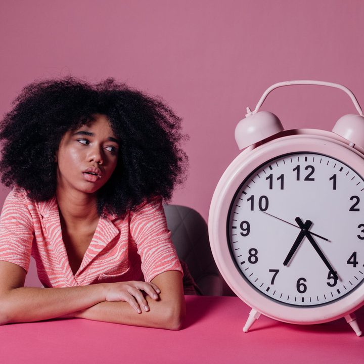 woman stares at large alarm clock