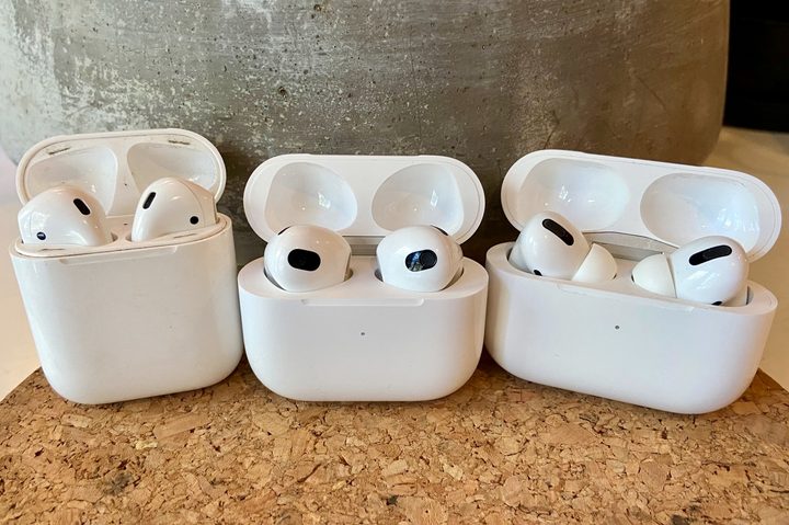 AirPods 3, AirPods, and AirPods Pro sitting in their charging cases.