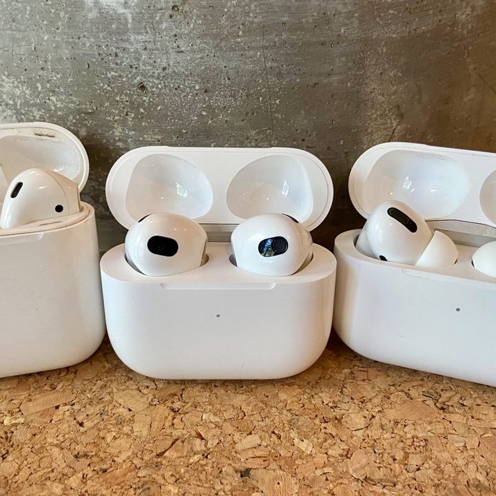 AirPods 3, AirPods, and AirPods Pro sitting in their charging cases.