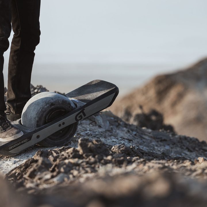 Onewheel GT with rider on a rocky trail.
