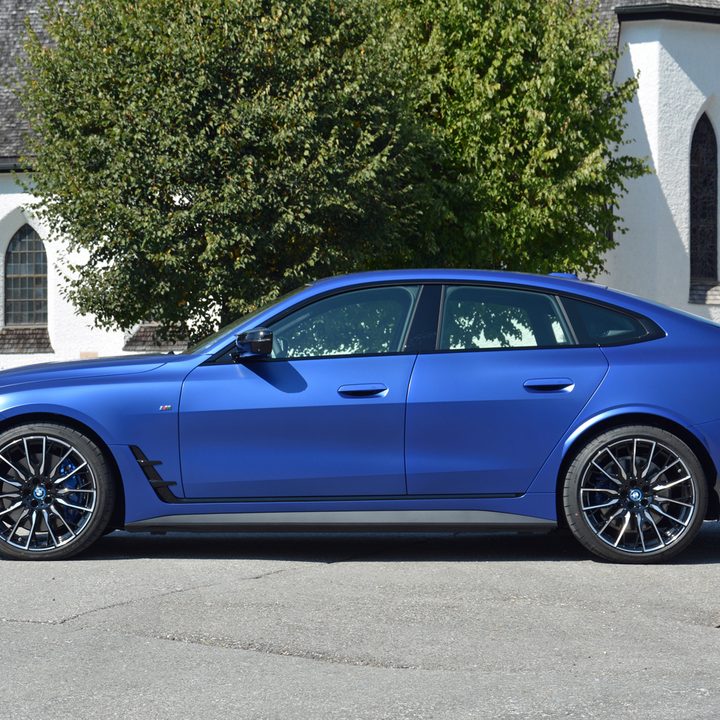 A 2022 BMW i4 M50 on pavement near a church.