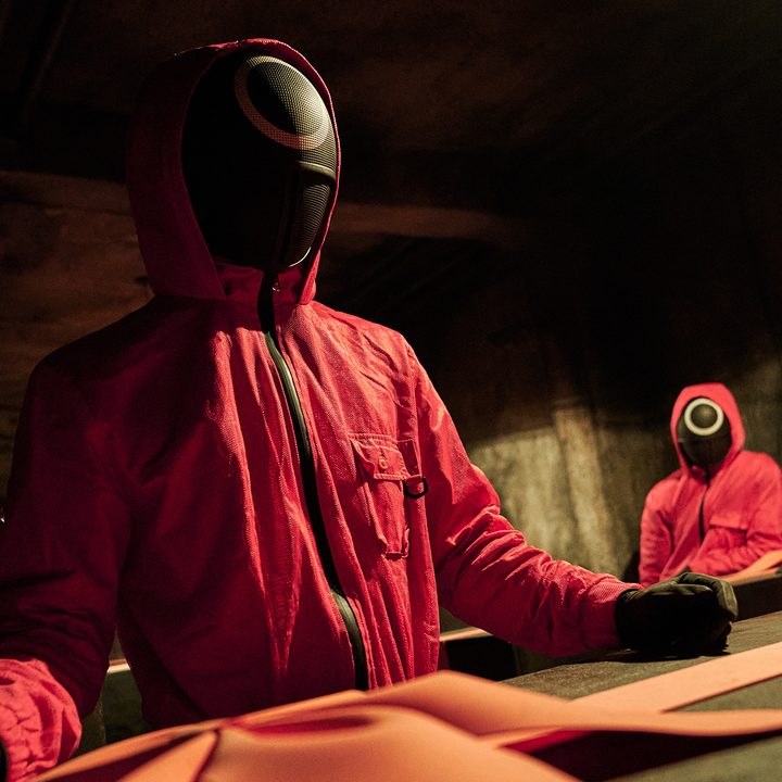 Workers from Squid Game standing over a casket.