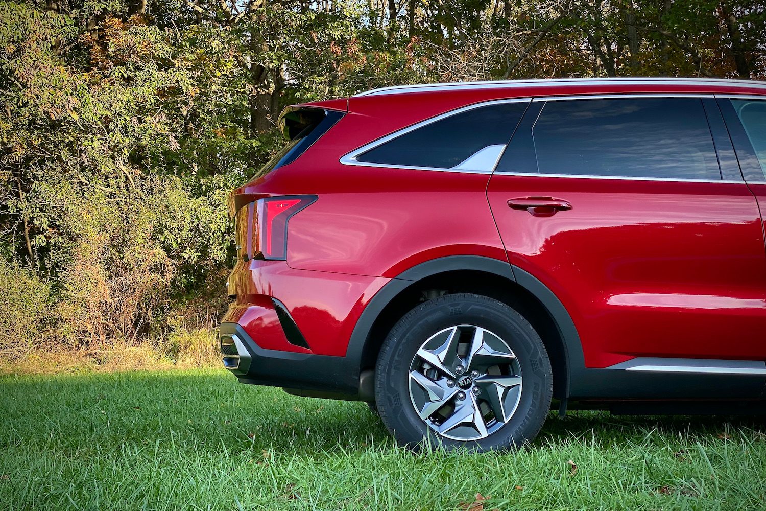 Rear half of the 2021 Kia Sorento Hybrid from the passenger side in a grassy field.