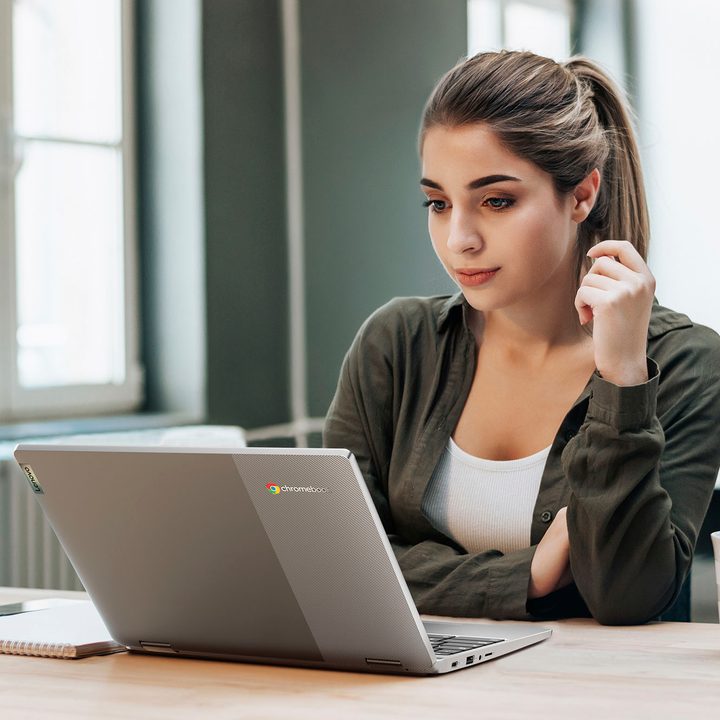 A woman sitting in front of an open Chromebook laptop.