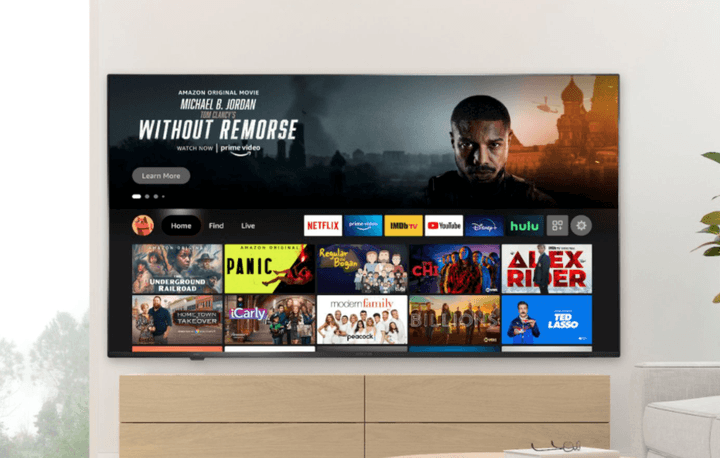 Insignia F50 QLED TV placed on a TV stand displaying streaming apps.