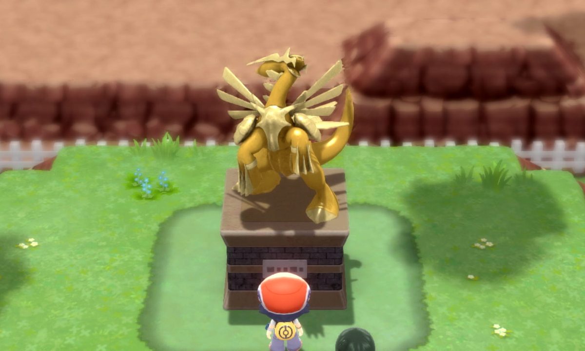 A trainer looks at a Dialga statue in Pokemon Brilliant Diamond and Shining Pearl.