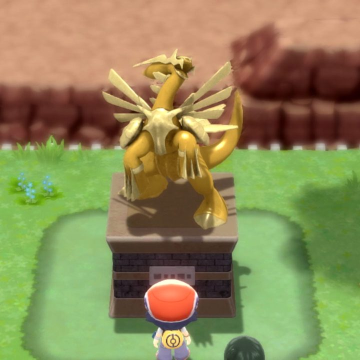 A trainer looks at a Dialga statue in Pokemon Brilliant Diamond and Shining Pearl.