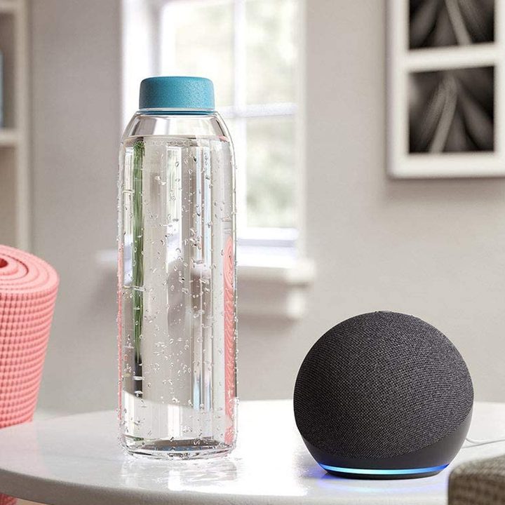 Amazon Echo Dot (4th Gen, 2020 release)on a table with a yoga matt and water bottle.