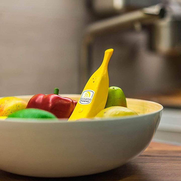 The banana phone sits in a bowl of fruit.