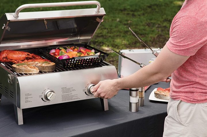 A person cooking food on the Cuisinart Chef's Style Table Top Grill.
