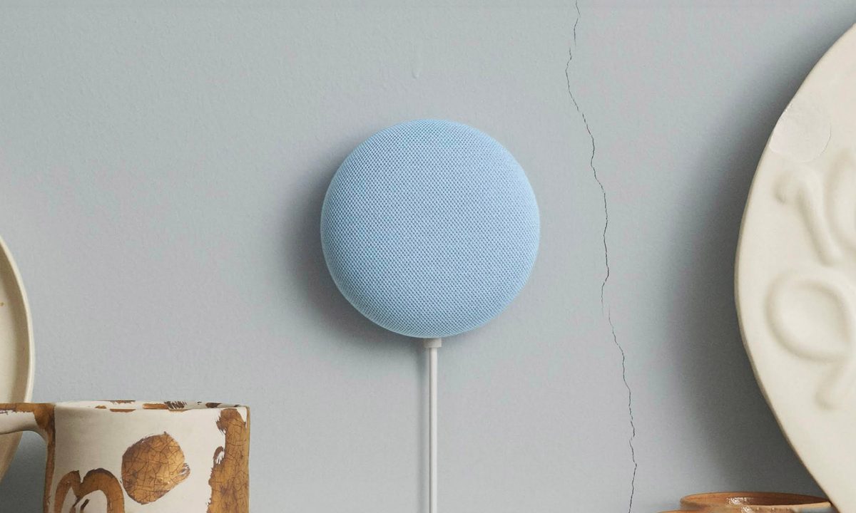 A blue Google Nest Mini mounted on blue/gray wall.