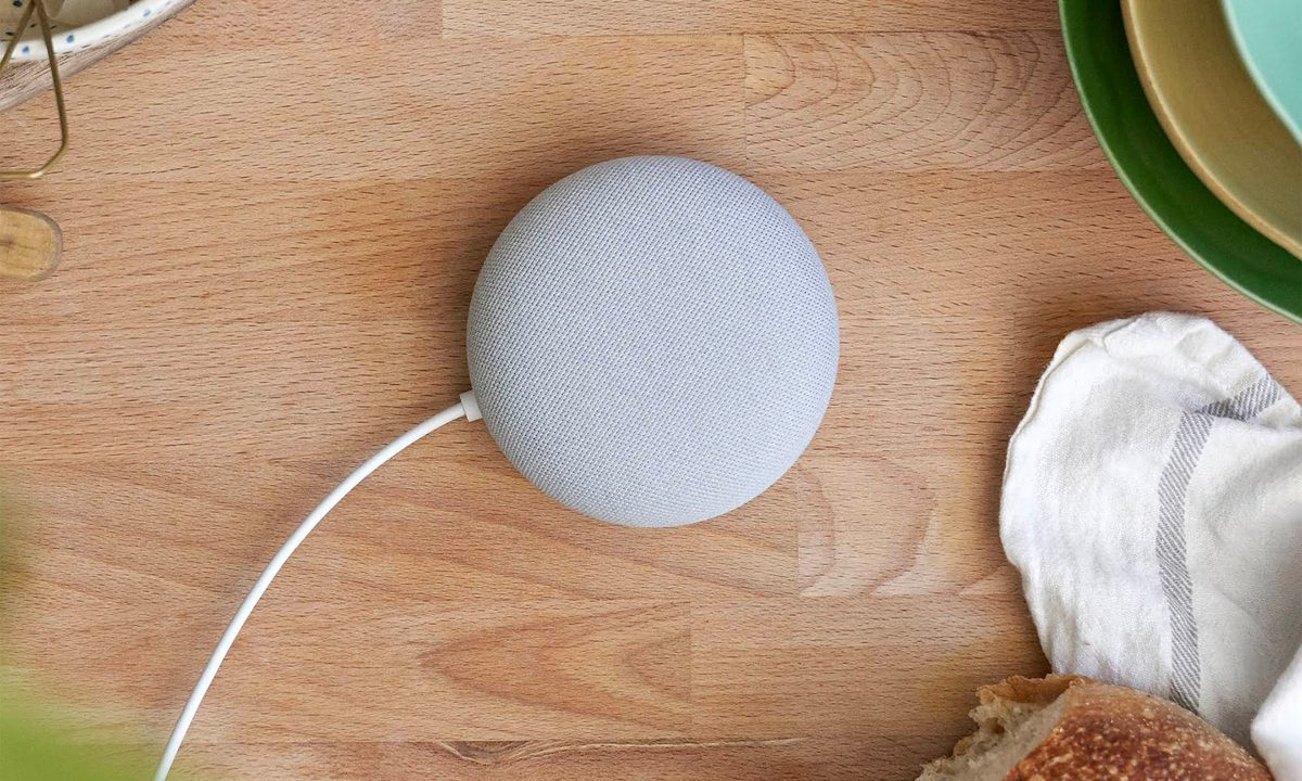 A gray Google Nest Mini sitting on a kitchen counter top.