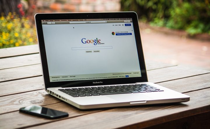 A laptop rests on a bench outside with google search open on-screen.