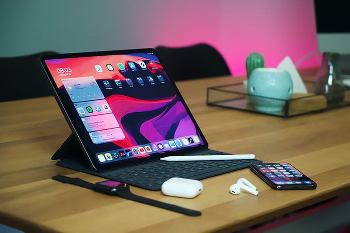 iPad Pro on a desk with AirPods and an iPhone nearby.