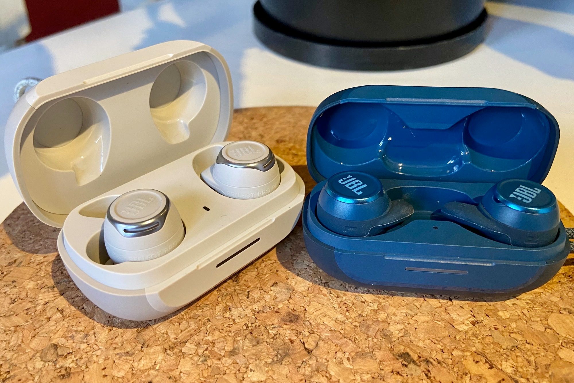 JBL Reflect Flow Pro charging case seen next to JBL Reflect Mini NC.