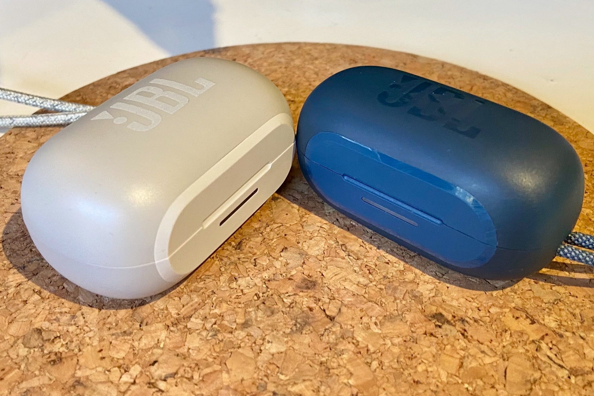JBL Reflect Flow Pro charging case seen next to JBL Reflect Mini NC charging case.