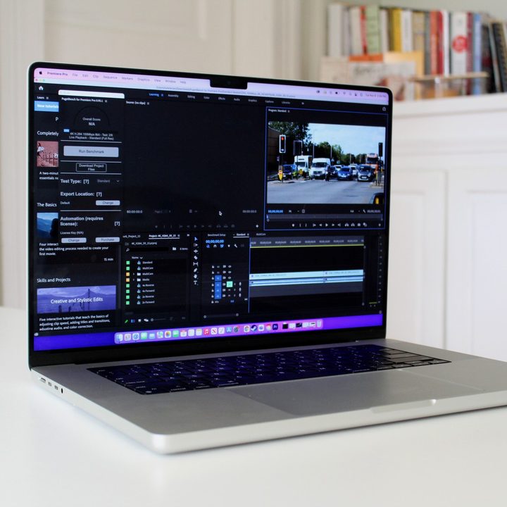 The Apple MacBook Pro an a white table with books on a shelf in the background.